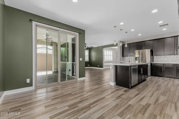 a large kitchen with stainless steel appliances granite countertop a large counter top a wooden floors and a large window