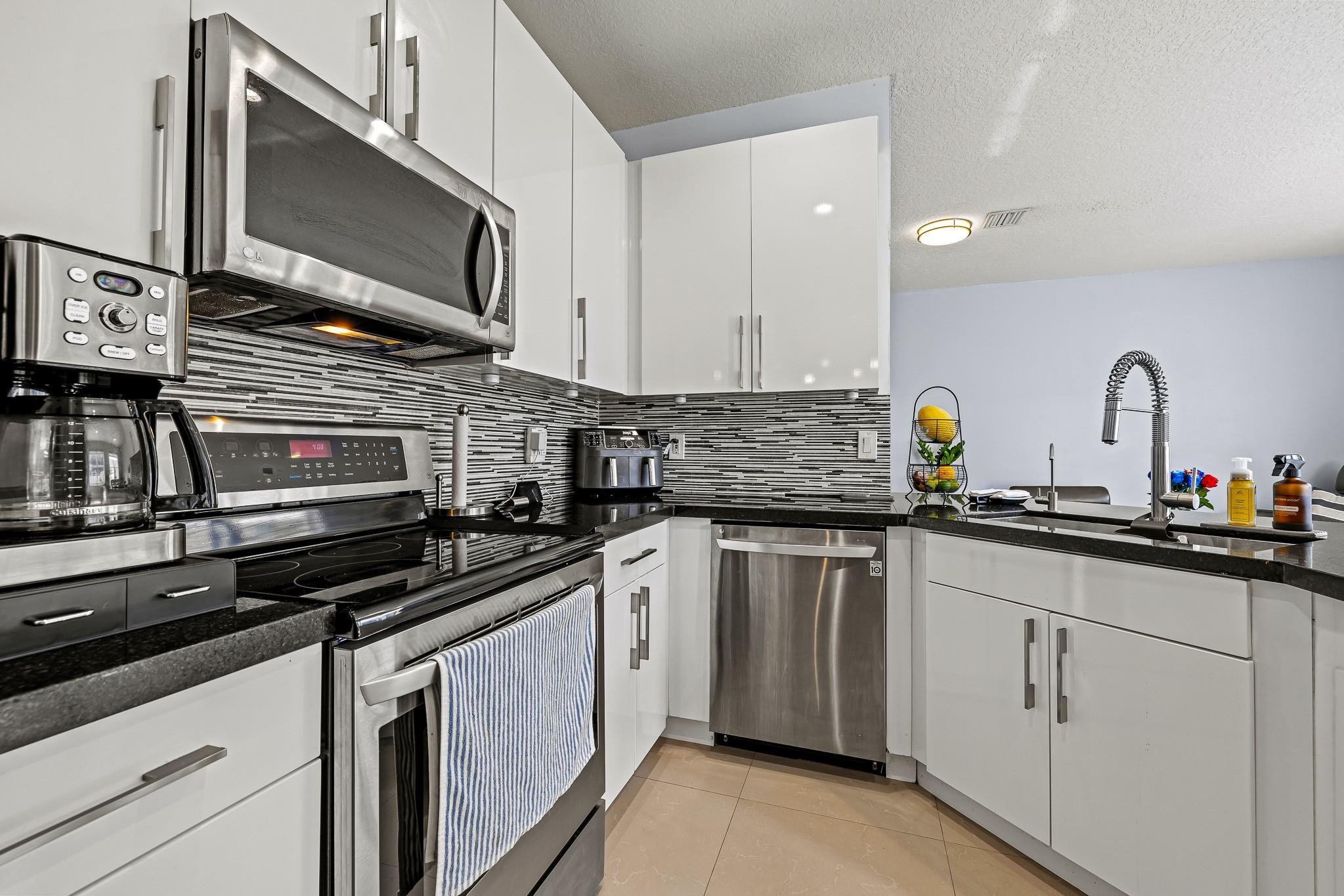 695 Falling Water Road Weston, FL 33326 - Photo 8 of 31 a kitchen with stainless steel appliances a sink stove and microwave
