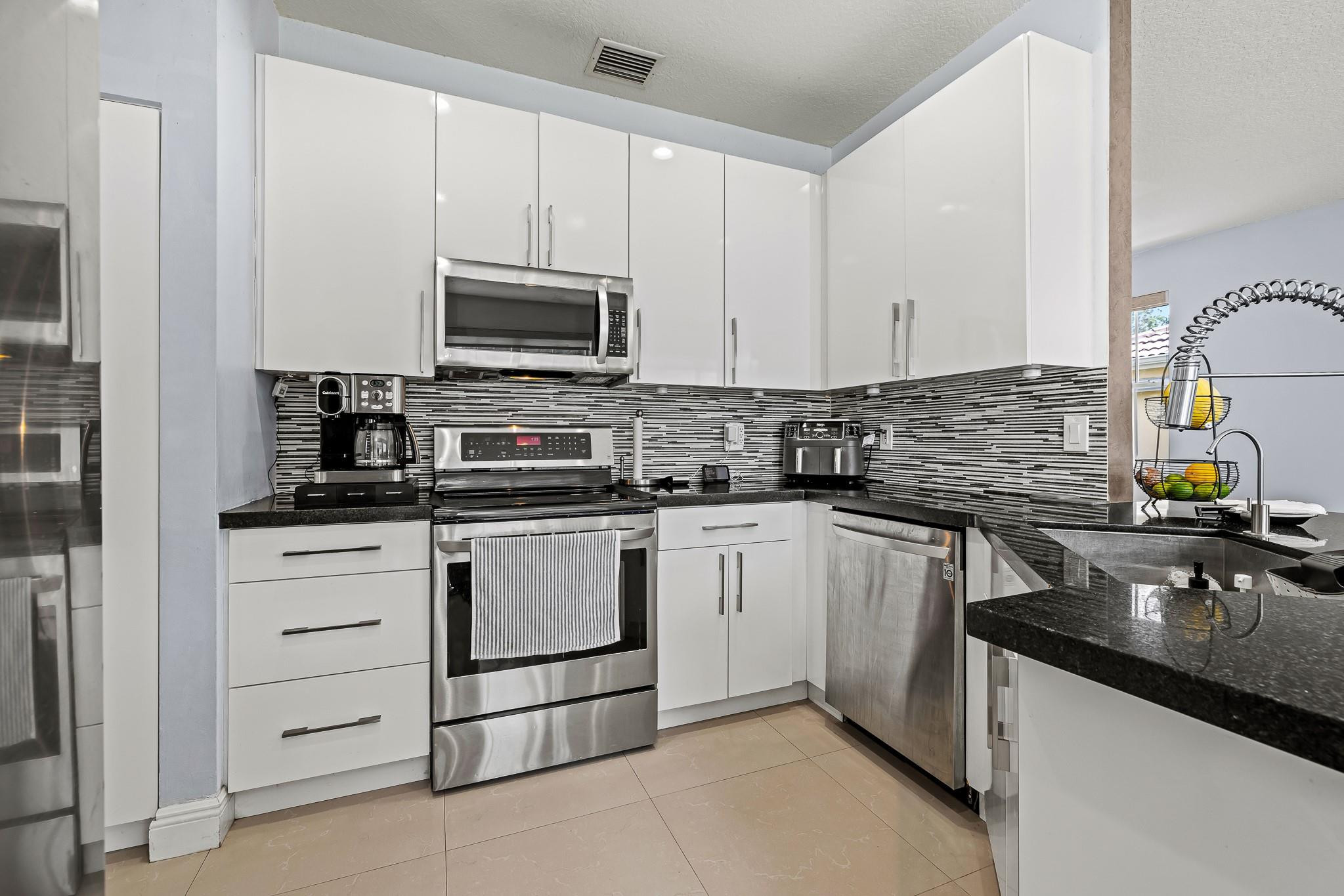 695 Falling Water Road Weston, FL 33326 - Photo 9 of 31 a kitchen with appliances a sink and cabinets