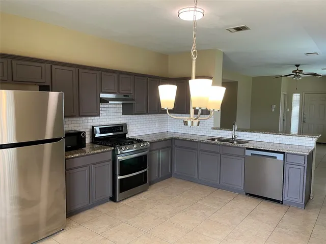a kitchen with stainless steel appliances granite countertop a refrigerator sink and stove