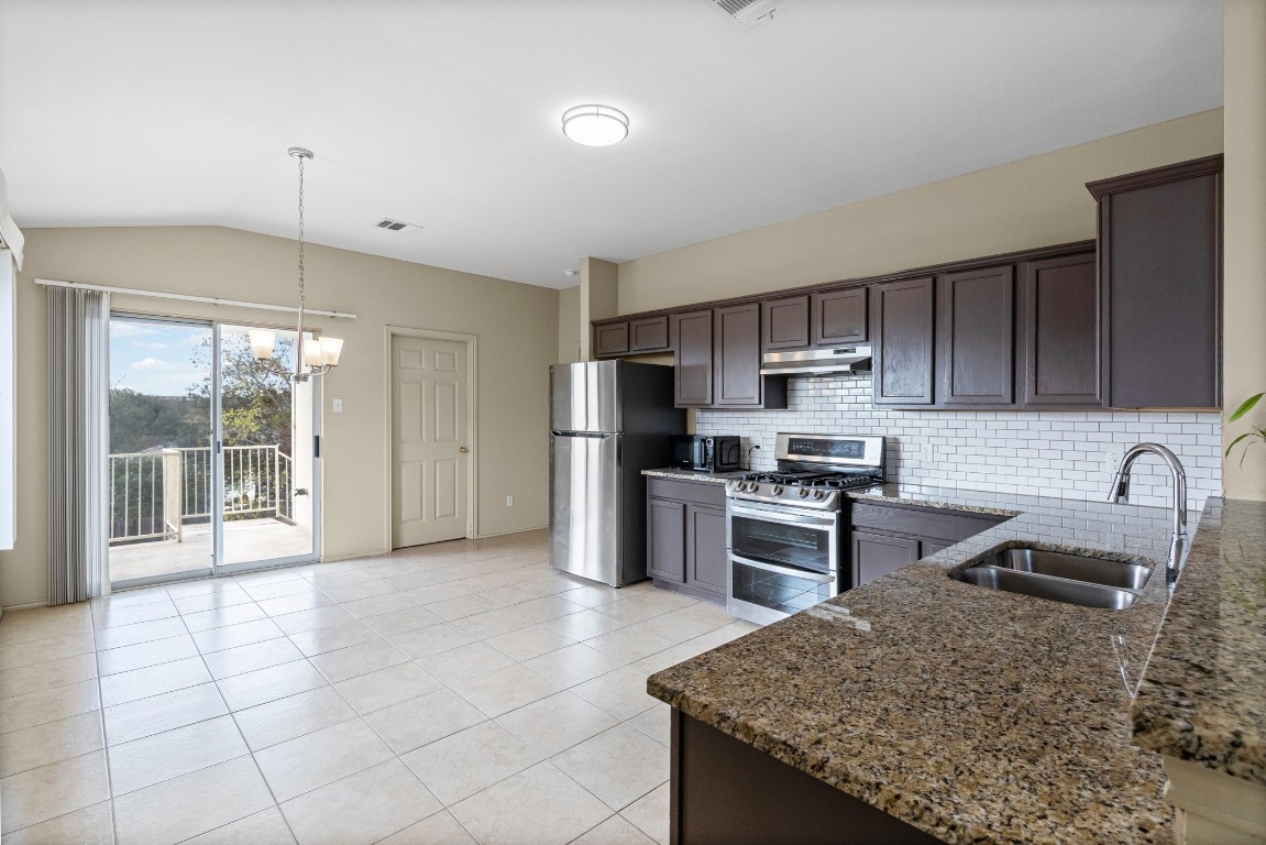 317 Tudor House Road Pflugerville, TX 78660 - Photo 5 of 28 a kitchen with stainless steel appliances granite countertop a sink stove and refrigerator