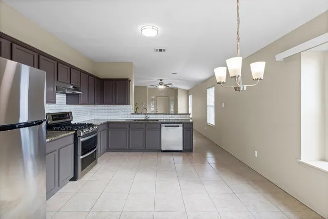 a large kitchen with a large counter top stainless steel appliances and cabinets