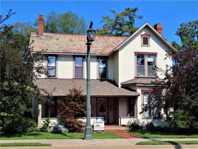 a front view of a house with a garden and trees