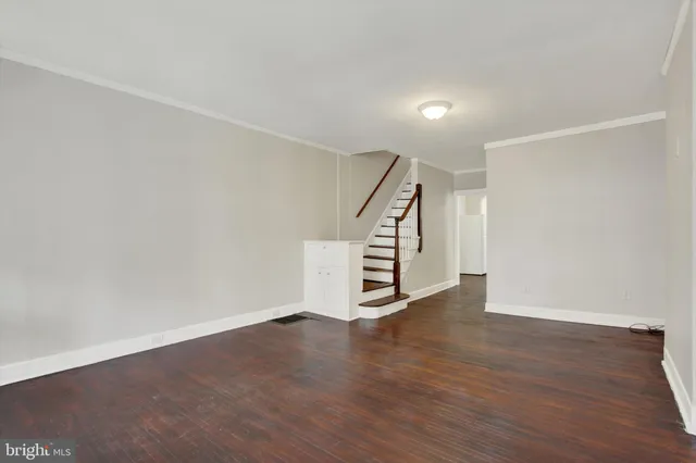 a view of an empty room with wooden floor and stairs