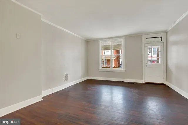 a view of an empty room with window and wooden floor