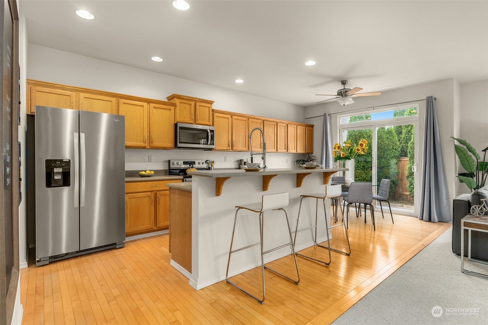 554 Rosario Avenue Northeast Renton, WA 98059 - Photo 5 of 38 a kitchen with stainless steel appliances granite countertop a refrigerator a stove a sink a dining table and chairs with wooden floor
