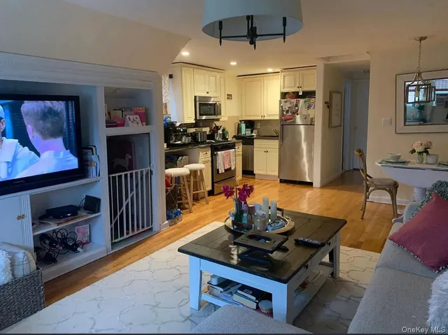 a kitchen with stainless steel appliances kitchen island granite countertop a refrigerator a stove and white cabinets with wooden floor