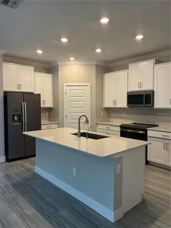 a kitchen with stainless steel appliances granite countertop a sink dishwasher a refrigerator and a stove with wooden floor