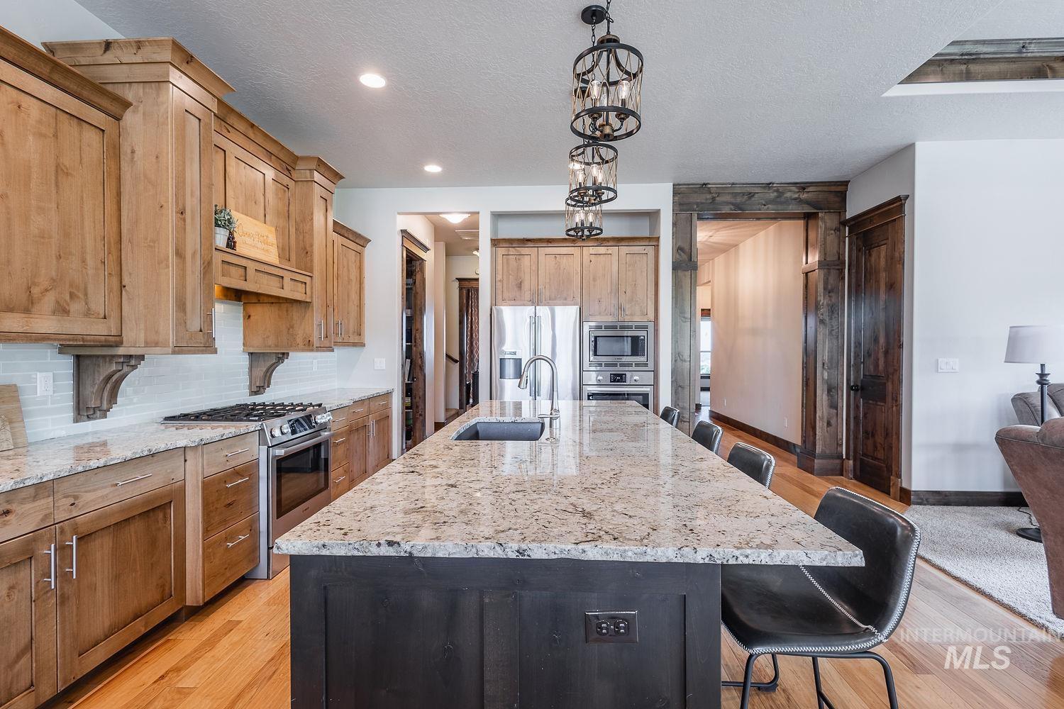 8077 Star Pass Ridge Road Nampa, ID 83686 - Photo 16 of 37 Living area featuring a stone fireplace with a built-in mantel, a wood-beam coffered ceiling with recessed lighting, and expansive windows