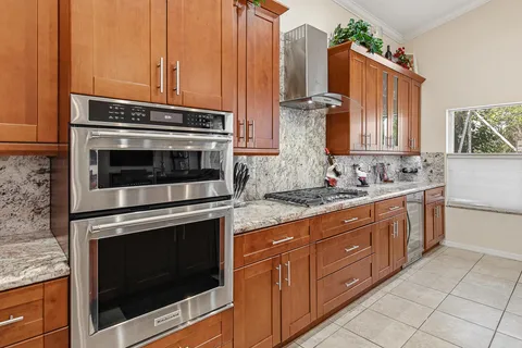 a large kitchen with stainless steel appliances granite countertop a sink stove and wooden cabinets