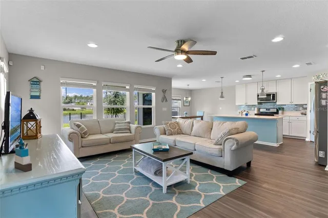 a living room with furniture kitchen view and a chandelier