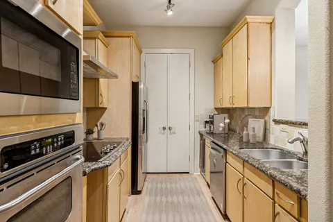a kitchen with stainless steel appliances granite countertop a sink stove and refrigerator