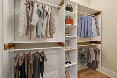 a view of walk in closet with clothes and shoes