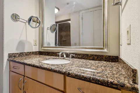 a bathroom with a granite countertop sink and a mirror