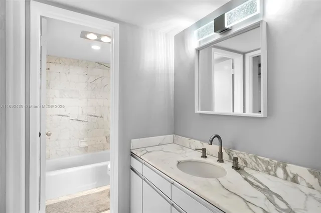 a bathroom with a granite countertop sink a mirror and a bathtub