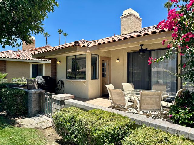 a view of a patio with table and chairs potted plants and a large tree