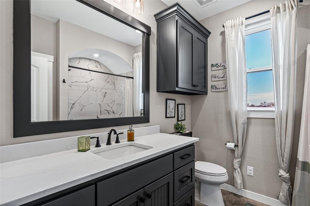 310 Runyan Rnch Road Tolar, TX 76476 - Photo 34 of 40 a bathroom with a granite countertop sink mirror vanity and toilet