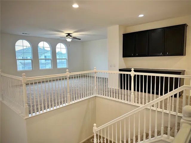 an empty room with windows and chandelier fan
