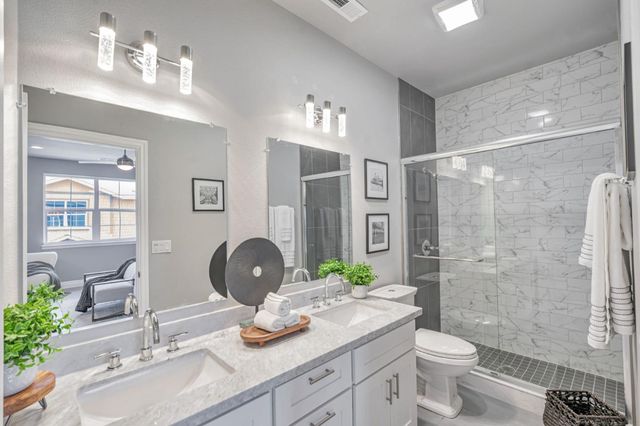 a bathroom with a granite countertop sink toilet a large mirror a shower and a mirror