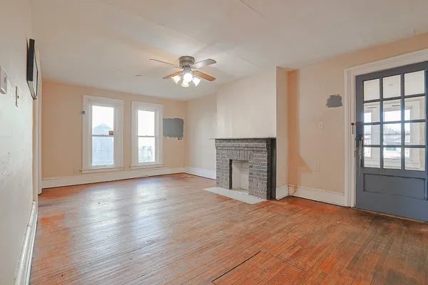a view of empty room with wooden floor and fan