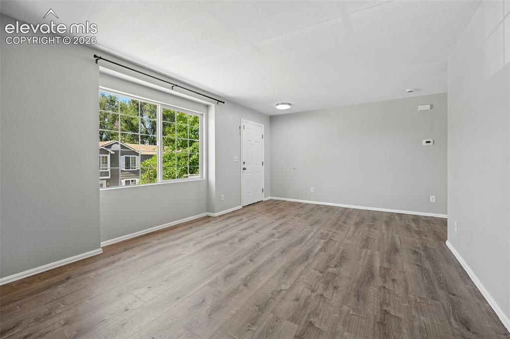 431 Kitfield View Colorado Springs, CO 80916 - Photo 11 of 27 an empty room with wooden floor and windows