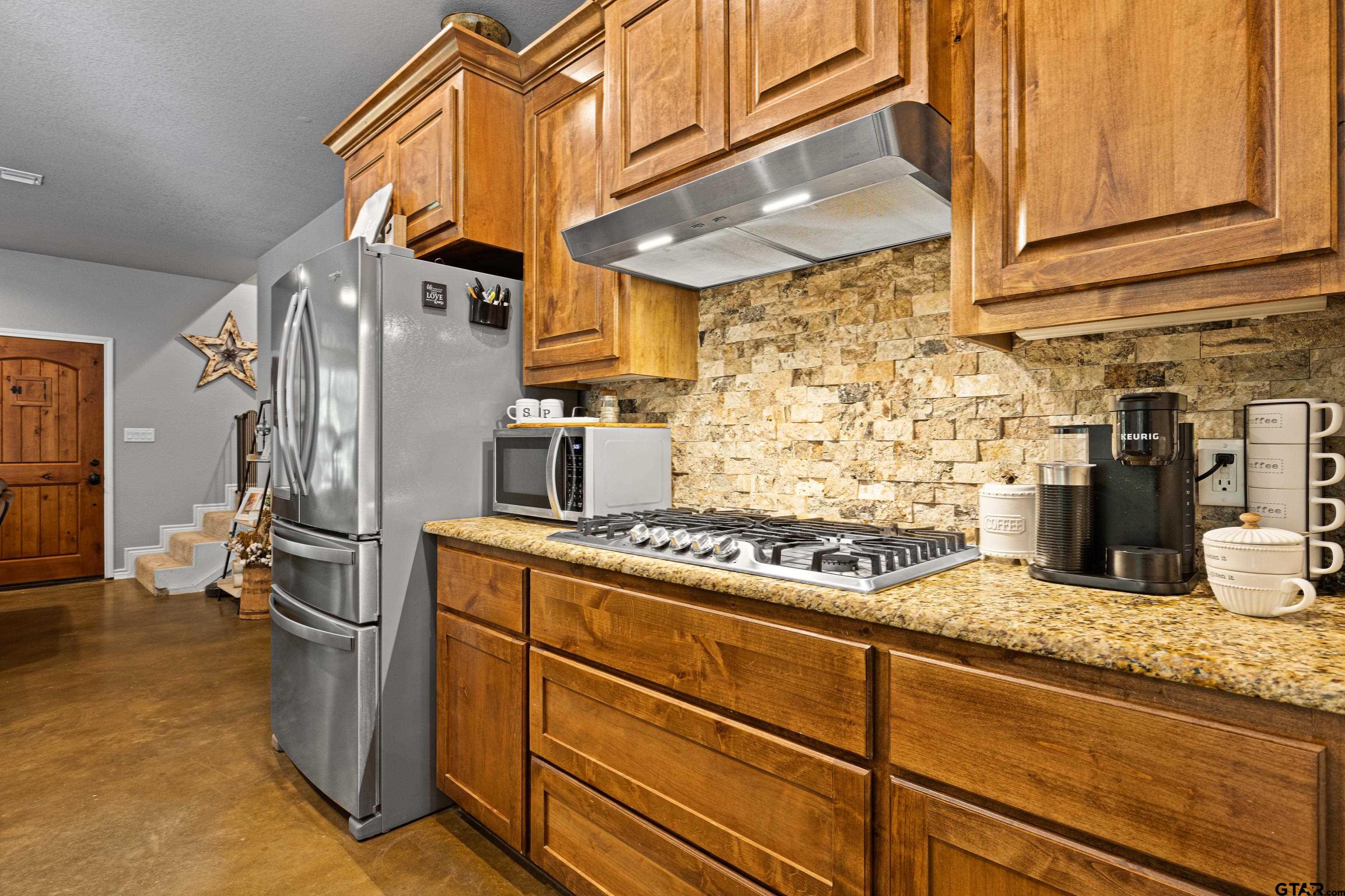 10586 Petunia Road Ore City, TX 75683 - Photo 20 of 45 a kitchen with stainless steel appliances granite countertop a stove and a refrigerator