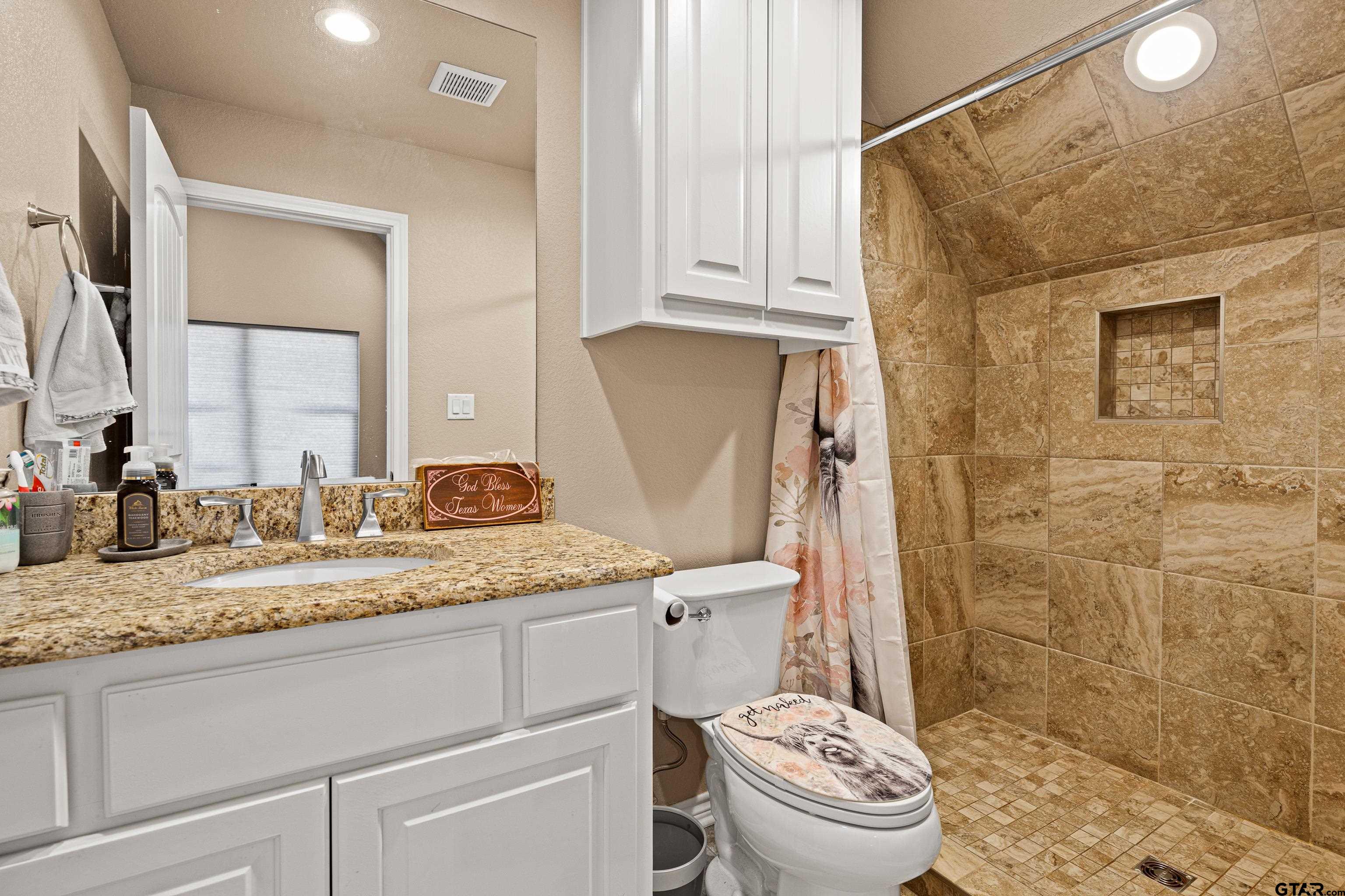 10586 Petunia Road Ore City, TX 75683 - Photo 33 of 45 a bathroom with a granite countertop sink toilet and shower