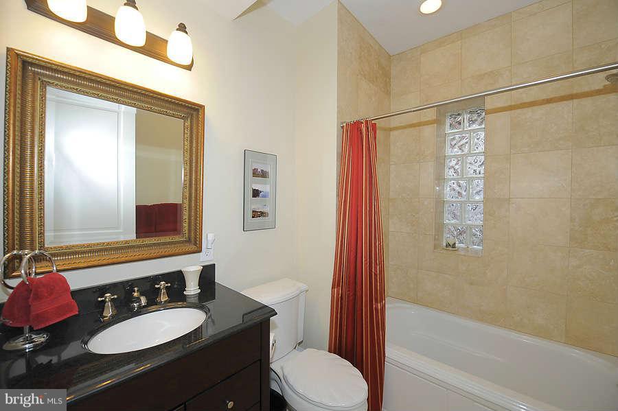 629 4th Street Northeast, Unit 3 Washington, DC 20002 - Photo 20 of 30 a bathroom with a granite countertop sink toilet a mirror a vanity and shower