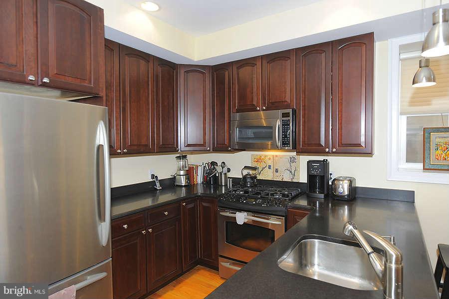 629 4th Street Northeast, Unit 3 Washington, DC 20002 - Photo 5 of 30 a kitchen with wooden cabinets a sink a stove and a refrigerator