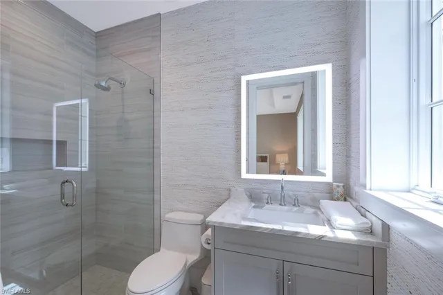 a bathroom with a granite countertop sink toilet a mirror and shower