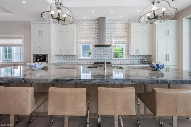a kitchen with granite countertop white cabinets white appliances dining table and chairs