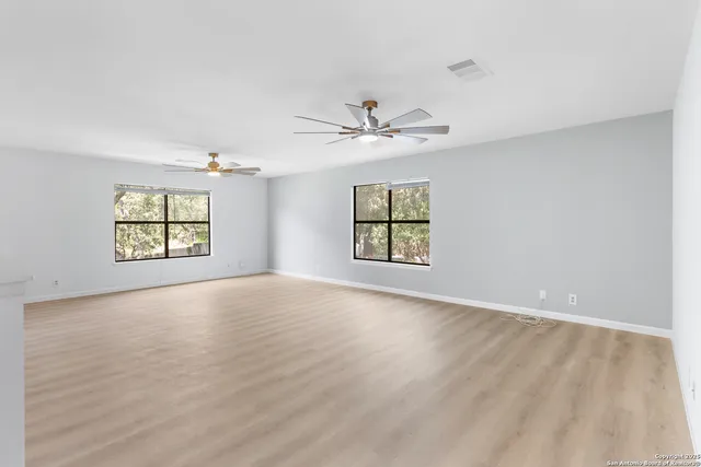an empty room with windows and ceiling fan