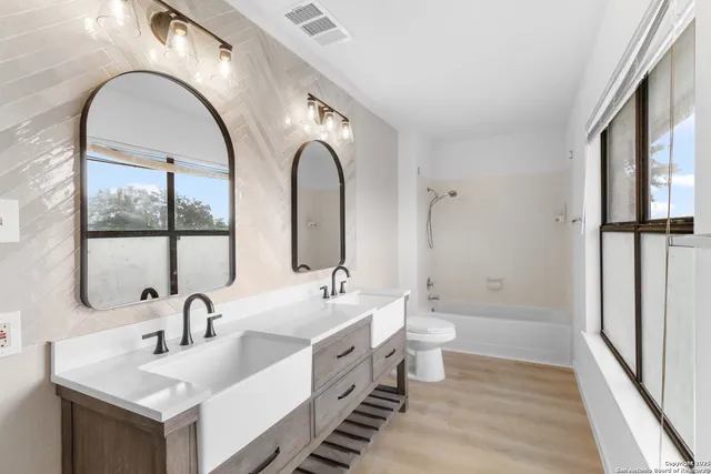 a spacious bathroom with a double vanity sink a mirror and a toilet