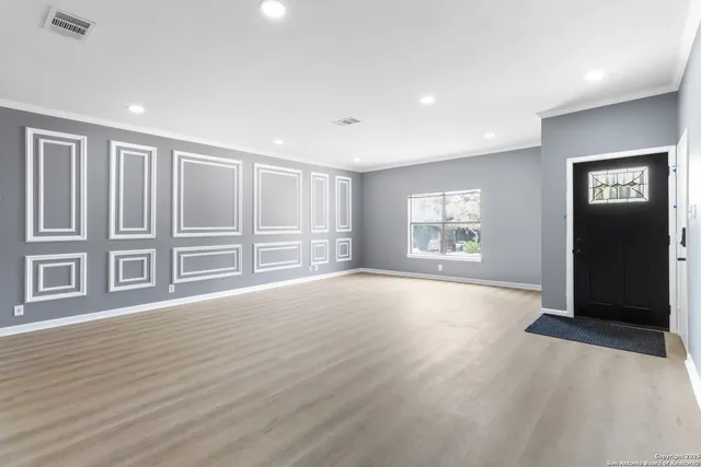 a view of an empty room with a window and wooden floor