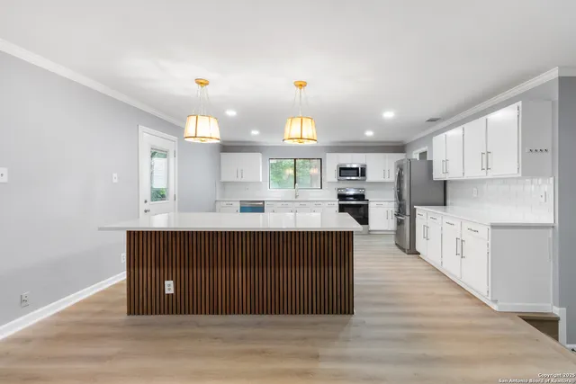 a kitchen with stainless steel appliances granite countertop a stove top oven a sink dishwasher and a refrigerator with wooden floor