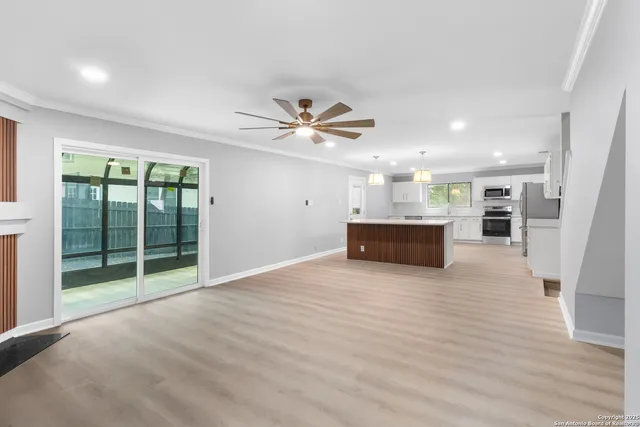 a view of an empty room with a window and kitchen view