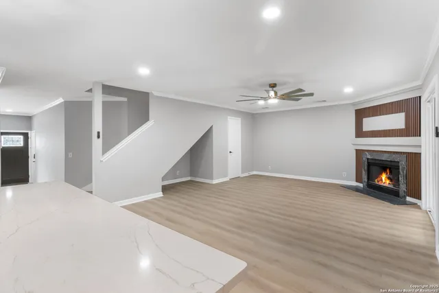 a view of an empty room with wooden floor fireplace and a window