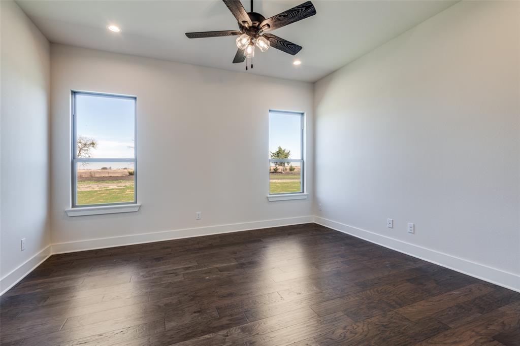 815 Evergreen Way Nevada, TX 75173 - Photo 19 of 38 an empty room with wooden floor ceiling fan and windows