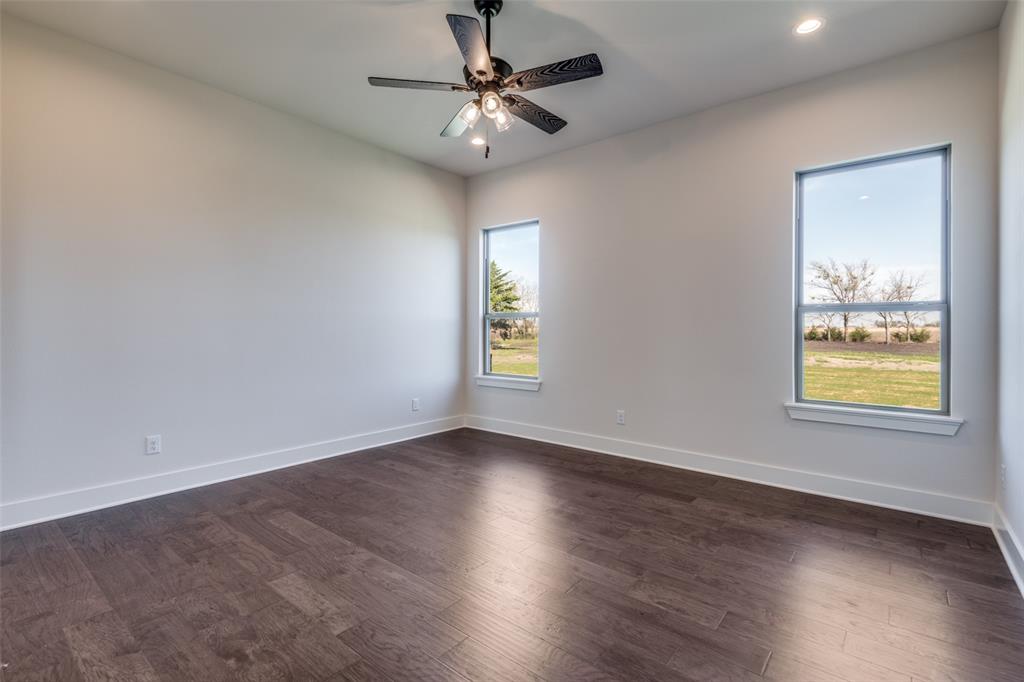 815 Evergreen Way Nevada, TX 75173 - Photo 20 of 38 an empty room with wooden floor chandelier fan and windows