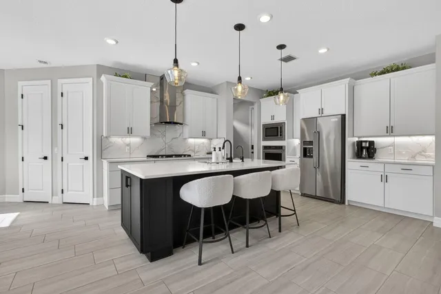 a kitchen with stainless steel appliances granite countertop a refrigerator a sink dishwasher a stove and white cabinets with wooden floor