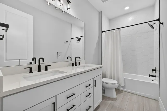 a bathroom with a double vanity sink toilet mirror and shower