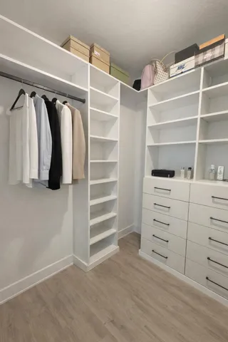 a view of walk in closet with clothes and shoes