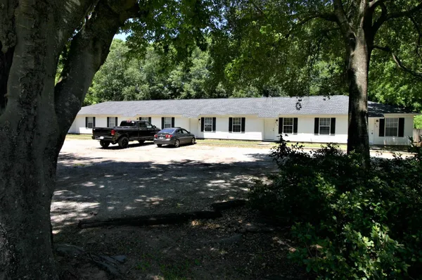 a view of house with yard outdoor seating and covered with trees