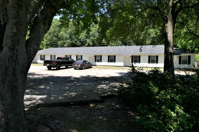 a view of house with yard outdoor seating and covered with trees