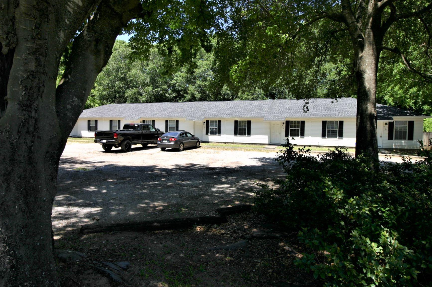 a view of house with yard outdoor seating and covered with trees