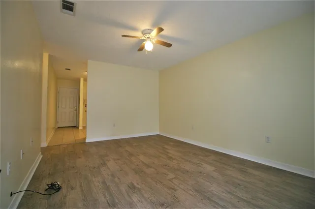 an empty room with wooden floor and fan