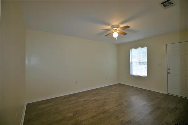an empty room with windows and chandelier fan