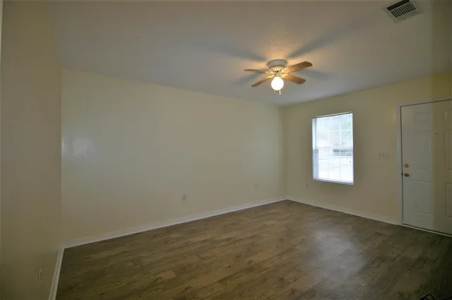 an empty room with windows and chandelier fan