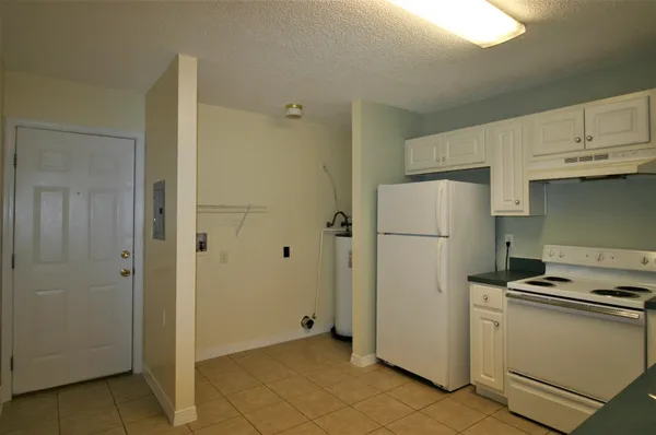 a view of a kitchen with refrigerator and white cabinets
