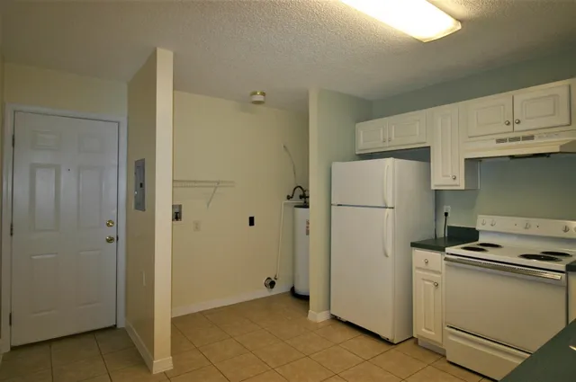 a view of a kitchen with refrigerator and white cabinets